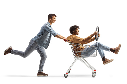 African american and caucasian male friends riding with a shopping cart isolated on white background