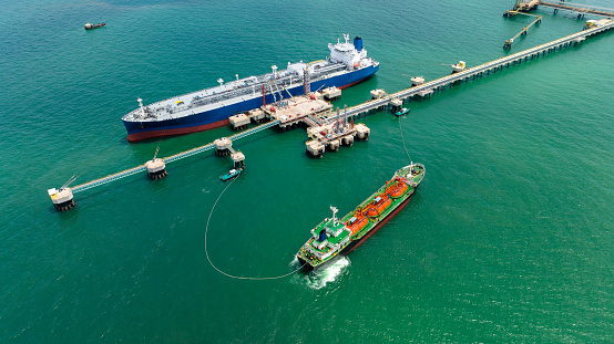 crude oil floating station in sea, bridge pipeline load unloading crude oil from oil ship transport, industry business transportation by container ship open sea, aerial drone point of view