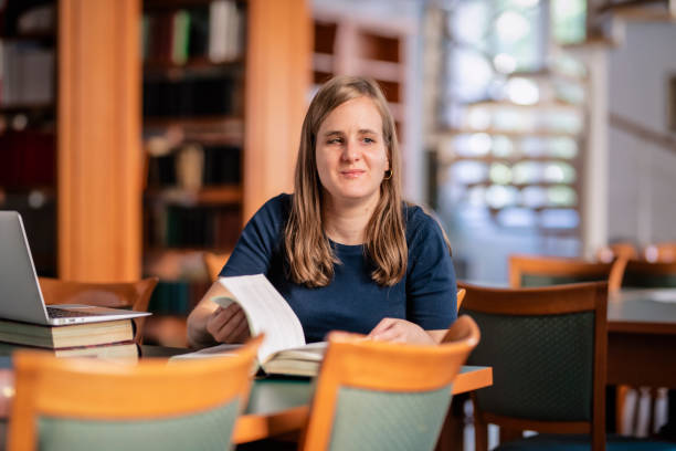 A visually impaired young woman sitting and studying in the university library stock photo