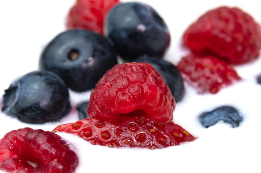 Close-up of a bowl with natural white yogurt and fresh raspberries, blueberries, strawberries, macro photography. Delicious healthy breakfast