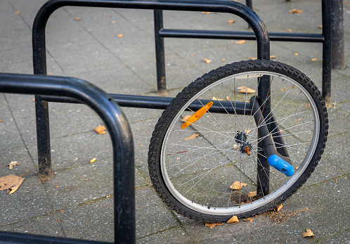 Germany, Berlin, September 10, 2023 -Protected bicycle wheel at a bicycle rack, Berlin Charlottenburg