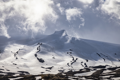 Majestic Landscape of Iceland's snow covered Mountain Peak of Snæfellsjökull Glacier Mountain Range in Summer under dramtic windy skyscape. Snow and Ice Covered Stratovolcano - Snaefellsjokull Mountain Peak. Snæfellsjökull Volcano, Western part of the Snæfellsnes - Snaefellsness Peninsula, Iceland, Nordic Countries, Northern Europe, Europe.