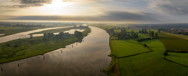 IJssel sunrise panoramic landscape view during a late summer morning near Zwolle. The river on the border of Overijssel and Gelderland is winding into the distance.