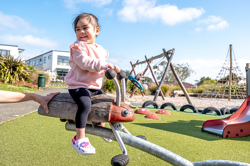 A cute toddler is playing on the seesaw