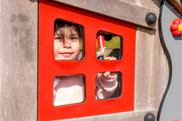 A Toodler looking through the window in a playground