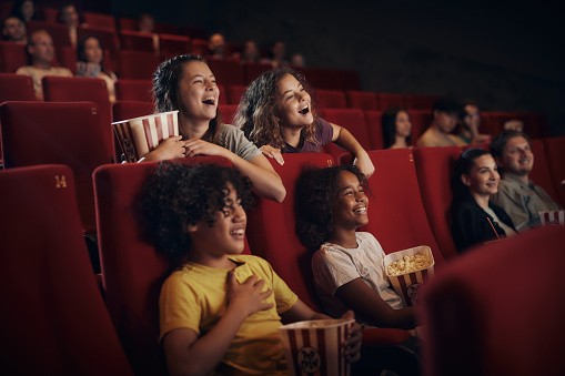 Group of happy little friends having fun while watching a comedy film in theatre.