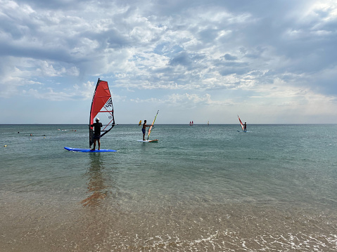 Surfers on beach on sunny day trying to catch wind in Torremolinos, Spain on July 4, 2023