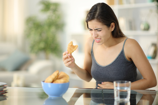 Glutton woman suffering stomach ache eating bakery
