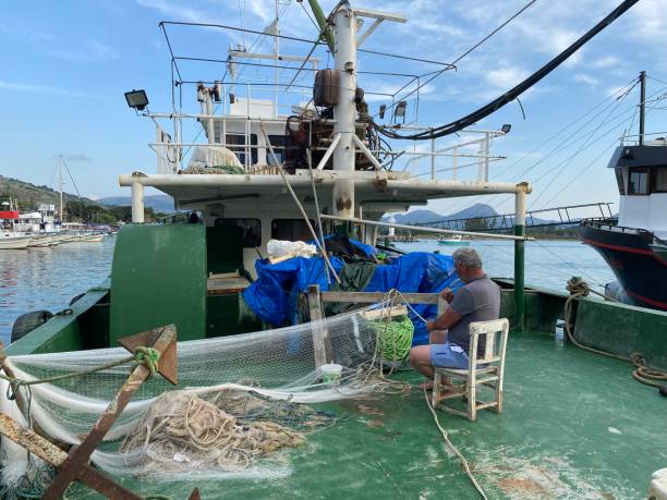 un pescatore sconosciuto che tesse reti da pesca tradizionali sulla sua barca - turkish culture turkey fishing boat fishing foto e immagini stock