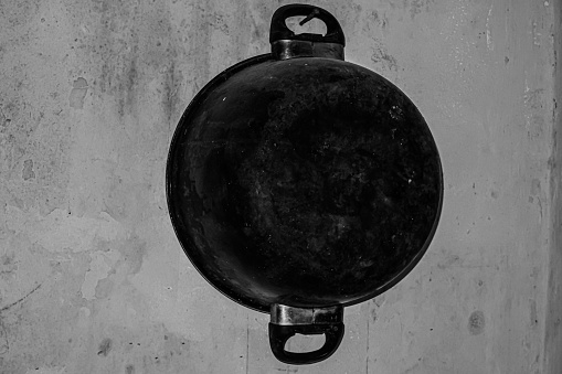 an old pan hanging on the wall is dirty and unkempt.