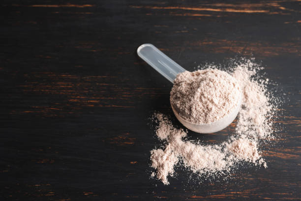 istock Whey chocolate protein powder in a plastic measuring spoon on a dark wooden background 1688376896