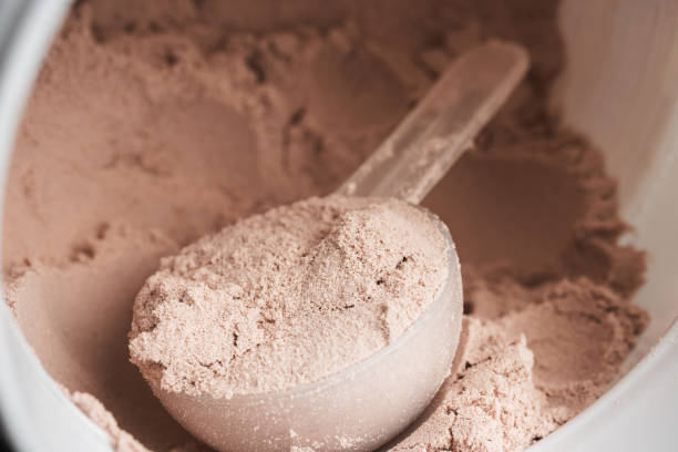 istock Scoop of chocolate whey protein isolate in a plastic jar, close-up view 1688382524