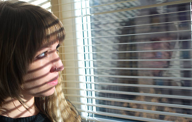 istock Sad girl looking through window 168838852
