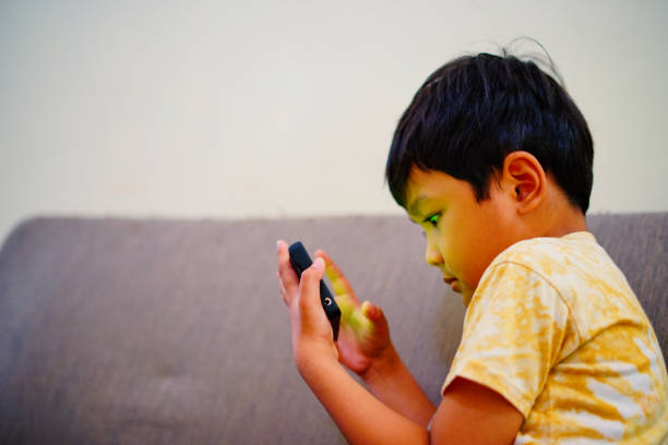 istock Asian boy watching video on smartphone on the gray sofa 1688404828