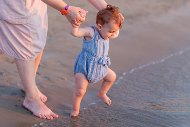 istock Mother and baby walking on sandy beach. Space for copy. 1688420830