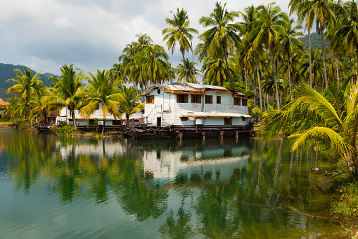 Koh Chang, Thailand - 14 Jan 2020: Marsh and palm tree landscape with an abandoned houseboat at Grand Lagoona, Koh Chang Island, in the Gulf of Thailand, Trat Province, Southeast Asia.
