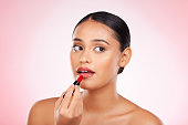 Red, lipstick and face of woman with makeup or cosmetics on pink background space and thinking about product. Lips, beauty and model with ideas for aesthetic skincare or choice of color on mouth