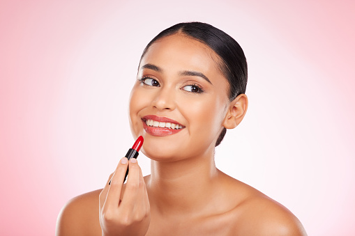 Lipstick, mockup and face of happy woman with makeup or cosmetics on pink background space and thinking about product. Lips, beauty and model with ideas for skincare or choice of red color on mouth