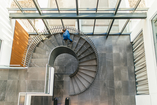 Spiral staircase with brown metal railing.  Perspective photography.  Indoor architecture.  Spiral staircase.