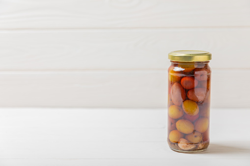 Olives in a glass jar on a concrete background. pitted  olives in jar.Pickled olives in glass jar. On a wooden background.Marinaded olives. Space for text.Space for copy. Vegan food.