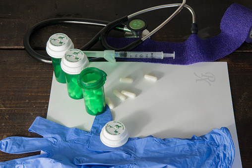Animal medications on a wooden table with prescription pad, gloves, gauze wrap, and stethoscope in a veterinarian office.