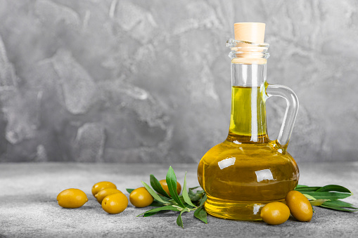 Olive oil in a bottle on a  texture background. Oil bottle with branches and fruits of olives. Place for text. copy space. cooking oil and salad dressing.
