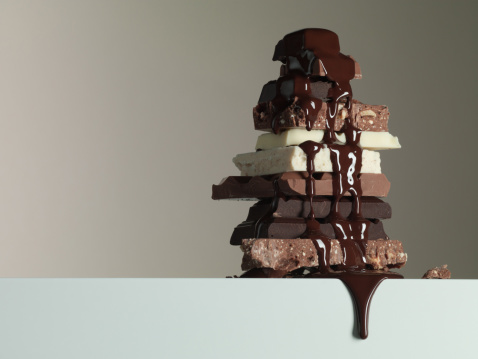 Dark chocolate bar pieces on dark background with grated chocolate, pile chunks of broken chocolate.