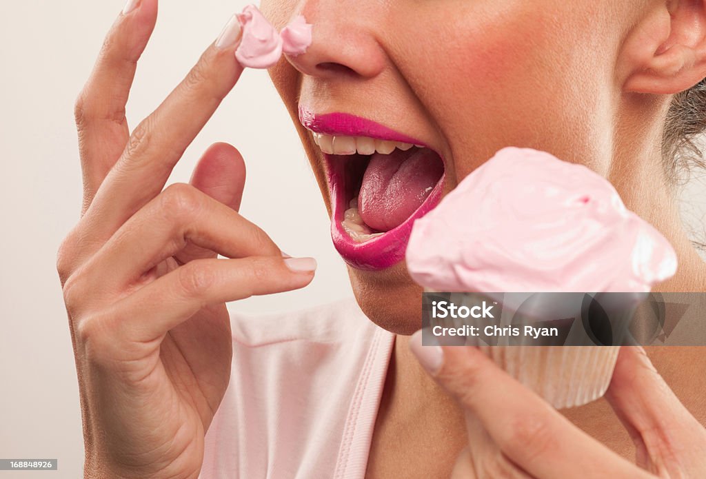 Kobieta z Różowa szminka i frosting na nos jedzenie cupcake - Zbiór zdjęć royalty-free (Jeść)