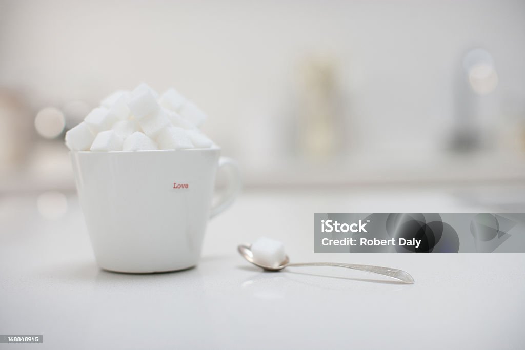Cubetti di zucchero riempimento tazza di caffè vicino a cucchiaio di zucchero cubo - Foto stock royalty-free di Abbondanza