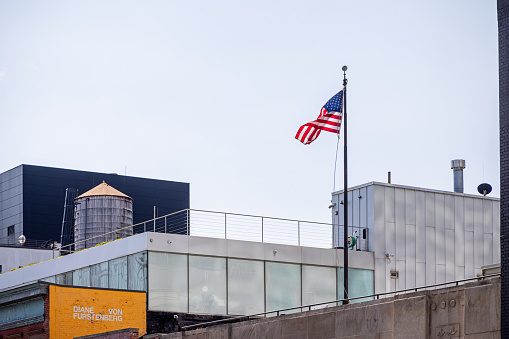 High Line Park, Manhattan, New York, USA - August 9th 2023:  Seen from the High Line Park: An American flag and a classic wooden water tank on the roof of a modern building