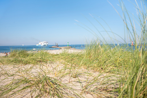 Rostock Warnemünde, Mecklenburg-Western Pomerania, Germany - September 9, 2023: View over the dunes to the Baltic Sea on the beach to the beacon at the old pier on a summer day.