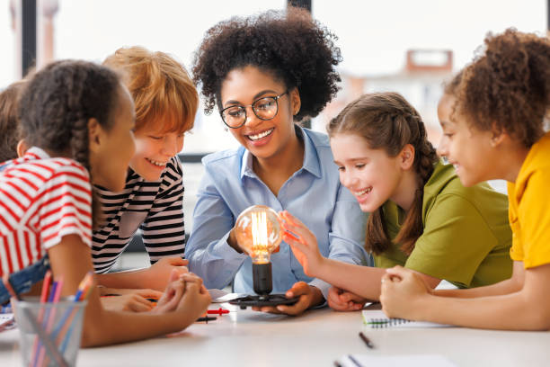 istock Multiethnic teacher and kids studying electricity and incandescent light bulb at physics lesson 1688516591