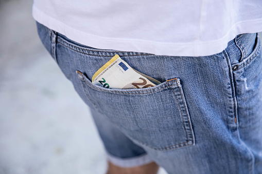 close-up of a man holding euro bills in his pants pocket