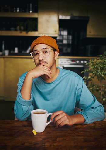Modern young man enjoying a cup of tea in his kitchen, stock photo, copy space