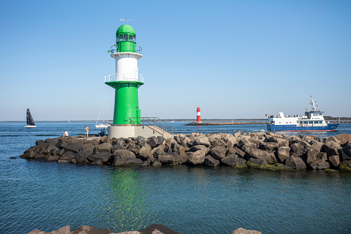 Rostock Warnemünde, Mecklenburg-Western Pomerania, Germany - September 9, 2023: Historic green beacon on the old stream with tourists on the day in summer at the Baltic Sea.