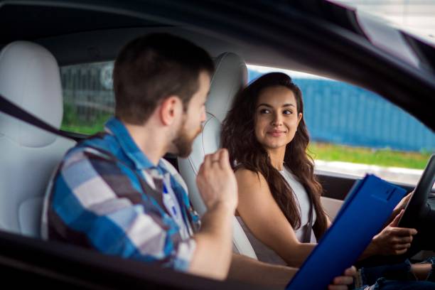 male instructor explaining rules for young woman during driving school training, holding test report. test drive, transportation, safety, education concept - driving training car safety imagens e fotografias de stock