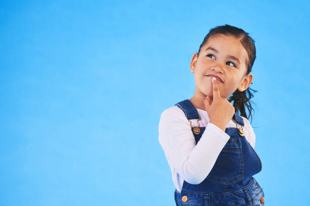 istock Thinking, child and girl with ideas, decision and choice on a blue studio background. Mockup space, kid and model with doubt, planning and inspiration with problem solving, question and opportunity 1688557290