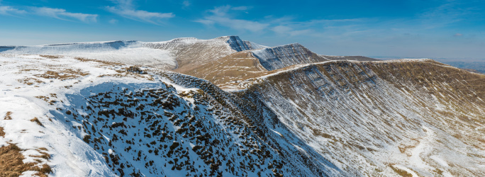 Panoramic vista across the wild mountain landscape of the Brecon Beacons Nation Park, across the snowy valleys to the peaks of Pen y Fan, Corn Du and Cribyn deep in the picturesque high country of Wales, UK. ProPhoto RGB profile for maximum color fidelity and gamut.