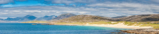 The golden sands, clear turquoise waters and green grass dunes of Seilebost, the idyllic ocean beach overlooked by the dramatic mountain peaks and wild remote landscape of the Isle of Harris, Outer Hebrides, Scotland. ProPhoto RGB profile for maximum color fidelity and gamut.