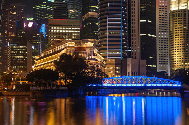 The neon lights and colourful glow of illuminated skyscrapers and hotels in the heart of Singapore's crowded Central Business District reflecting in the tranquil waters of the Singapore River below the Cavenagh Bridge. ProPhoto RGB profile for maximum color fidelity and gamut.