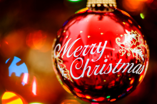 A red round Christmas tree ornament with Merry Christmas written on it.