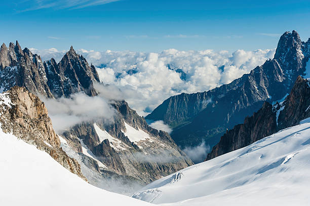 Alps snowy glaciers dramatic pinnacles above Chamonix France View from above the clouds across the bright white glaciers, dramatic rocky pinnacles and high altitude summits of the Mont Blanc Massif and the Vallee Blanche from the Pointe Helbronner in Italy past the iconic Alpine peaks of the Aiguille du Midi to the Aiguille Verte and Les Drus, and down the Glacier du Geant down to the Chamonix valley in France. ProPhoto RGB profile for maximum color fidelity and gamut. glacier photos stock pictures, royalty-free photos & images