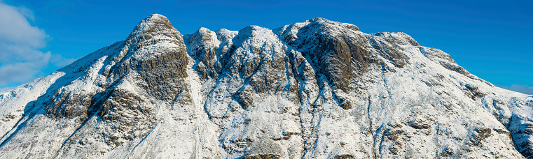 The iconic rocky peaks and pinnacles, snow capped summits and vertiginous scree slopes of the Langdale Fells, from the dome of Pike O'Stickle and the cliffs of Glimmer Crag to heights of Harrison Stickle, glistening in the crisp winter air under deep blue skies in this large and extremely detailed panoramic vista across Mickleden in the heart of England's beautiful Lake District National Park, Cumbria, UK. ProPhoto RGB profile for maximum color fidelity and gamut.