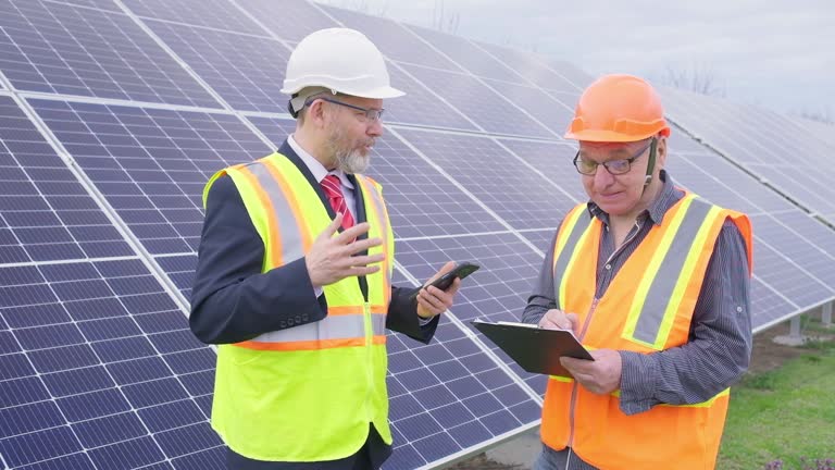 A manager and a worker are talking in a park with solar panels.