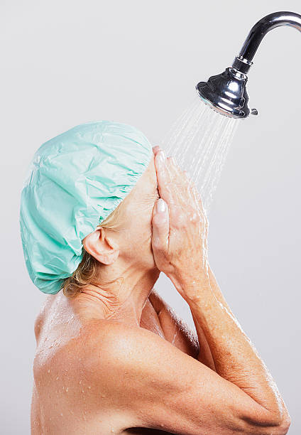 Woman in Shower A mature woman standing in a shower. shower women falling water human face stock pictures, royalty-free photos & images