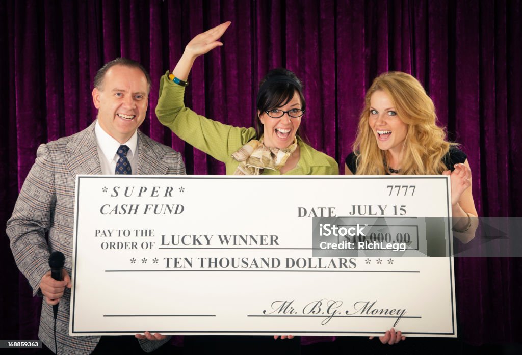 Game Show Winner An old fashioned game show host holding a microphone standing with the contestant and assistant. Photographed in studio with a purpose built set and props. Lottery Stock Photo