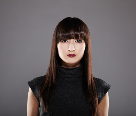 Portrait of a beautiful Japanese woman isolated on gray background. Vertical composition.