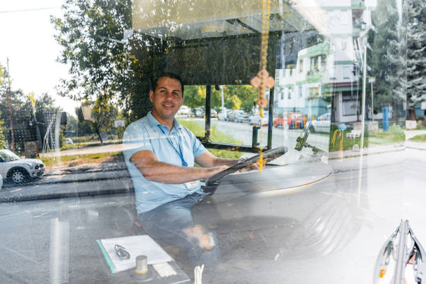 un homme adulte conduit un autobus dans la rue - traffic car street parking photos et images de collection