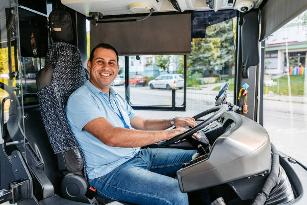 un homme adulte conduit un autobus dans la rue - driving a car photos et images de collection