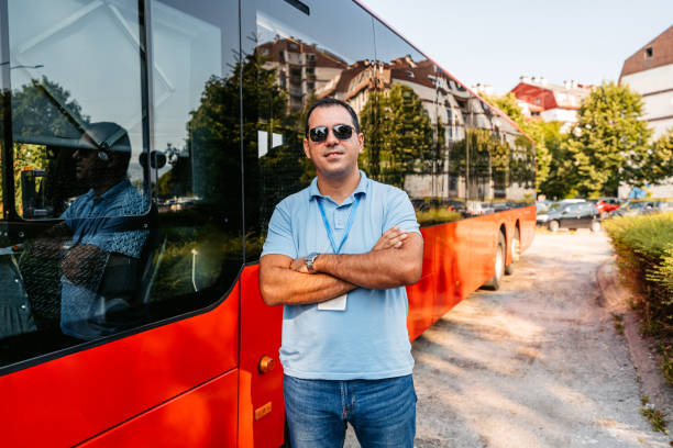 chauffeur de bus mid adult debout devant un bus - traffic car street parking photos et images de collection
